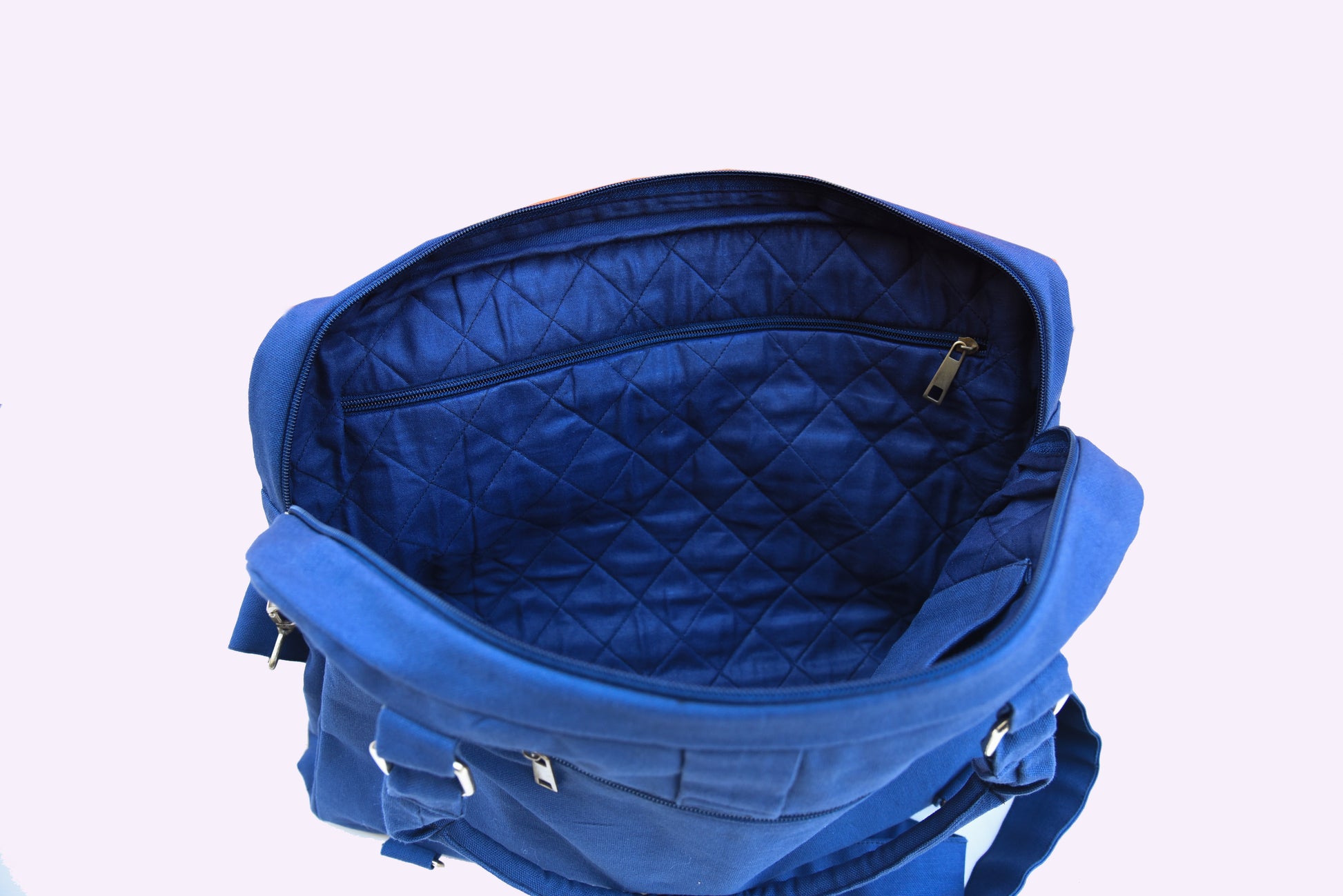 Close-up of the interior of a blue canvas laptop bag, showcasing quilted lining and a zipper pocket