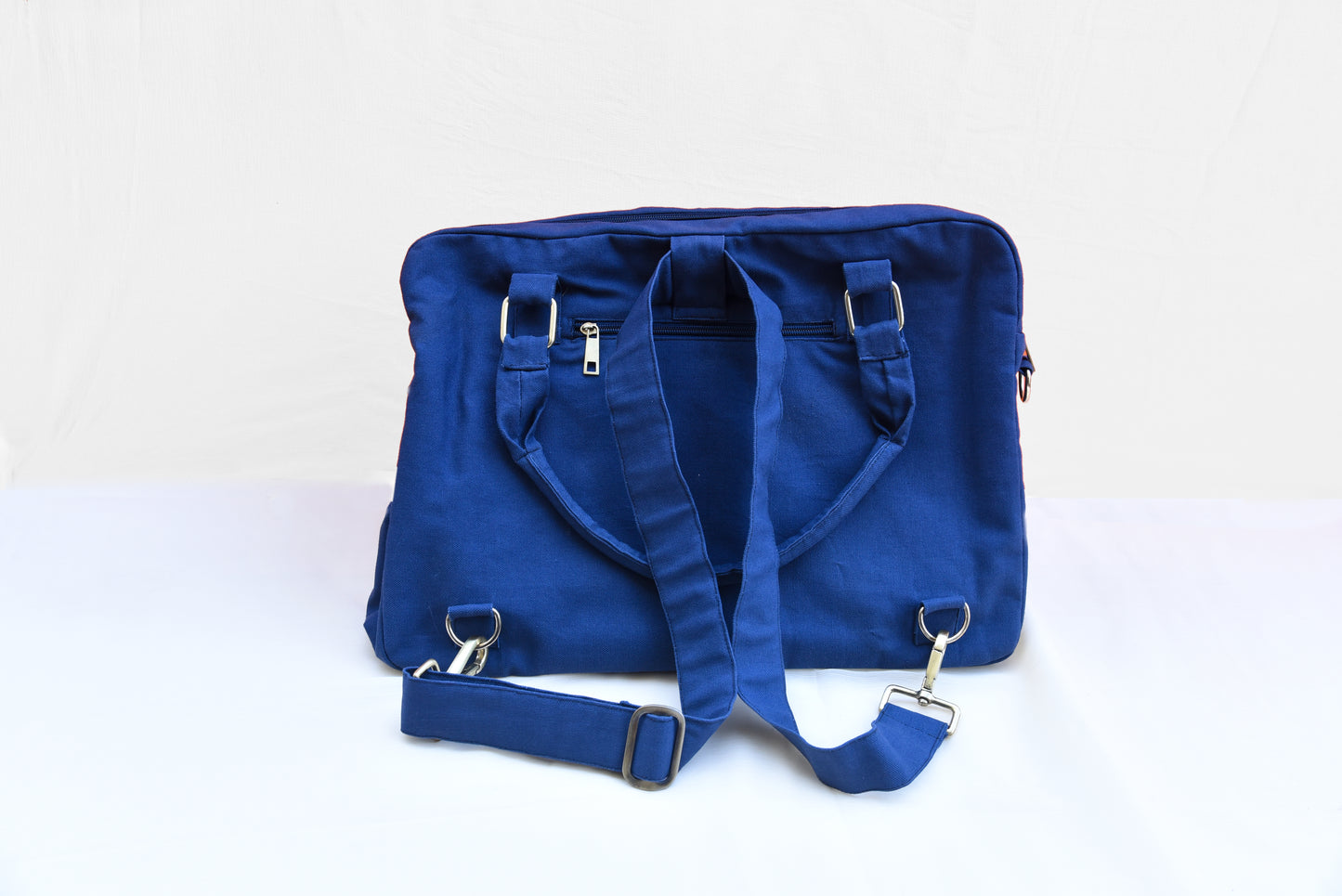 A close up image of the back side of a blue canvas convertible bag and a back pocket 